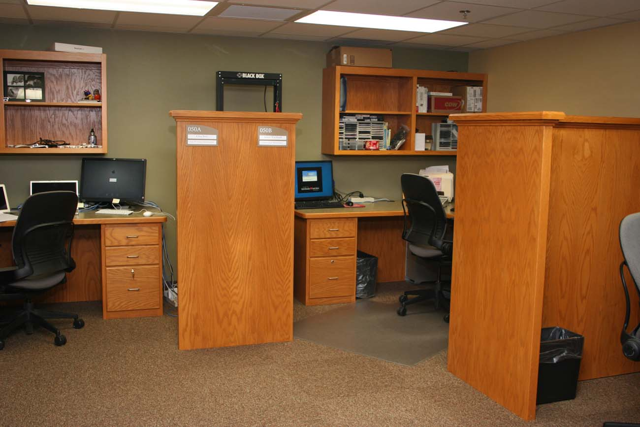 A cubicle in an office with a laptop on the desk