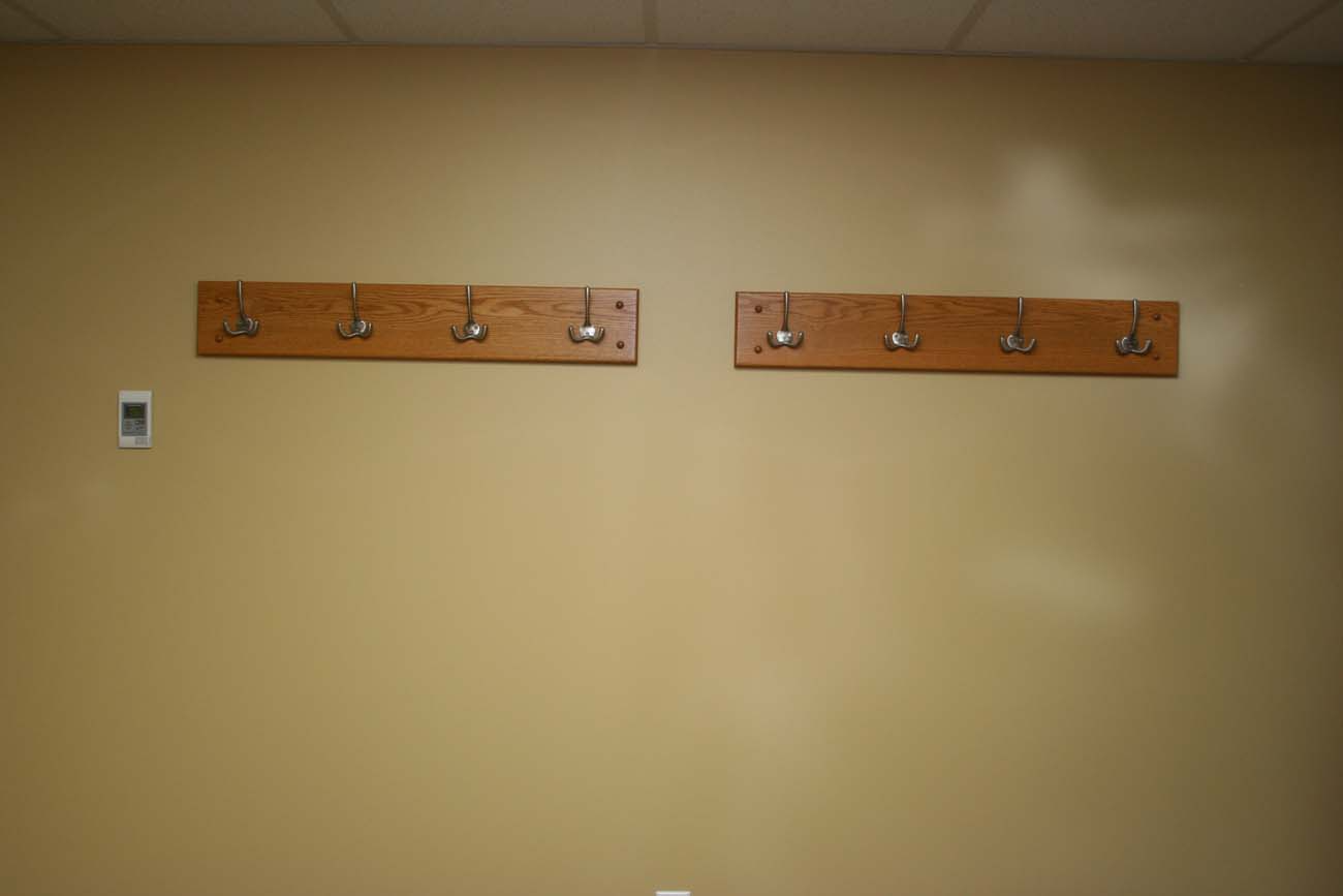 Two wooden hooks hanging on a tan wall