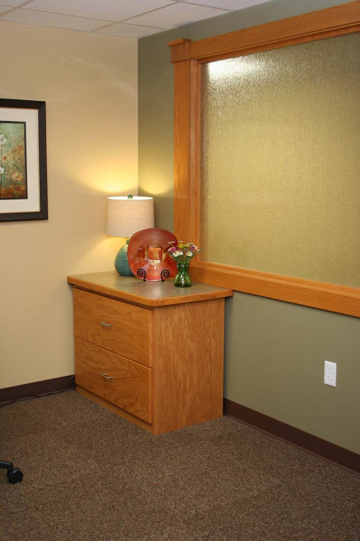 A room with a dresser a lamp and a picture on the wall