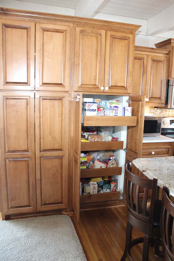 A kitchen with wooden cabinets and drawers filled with food