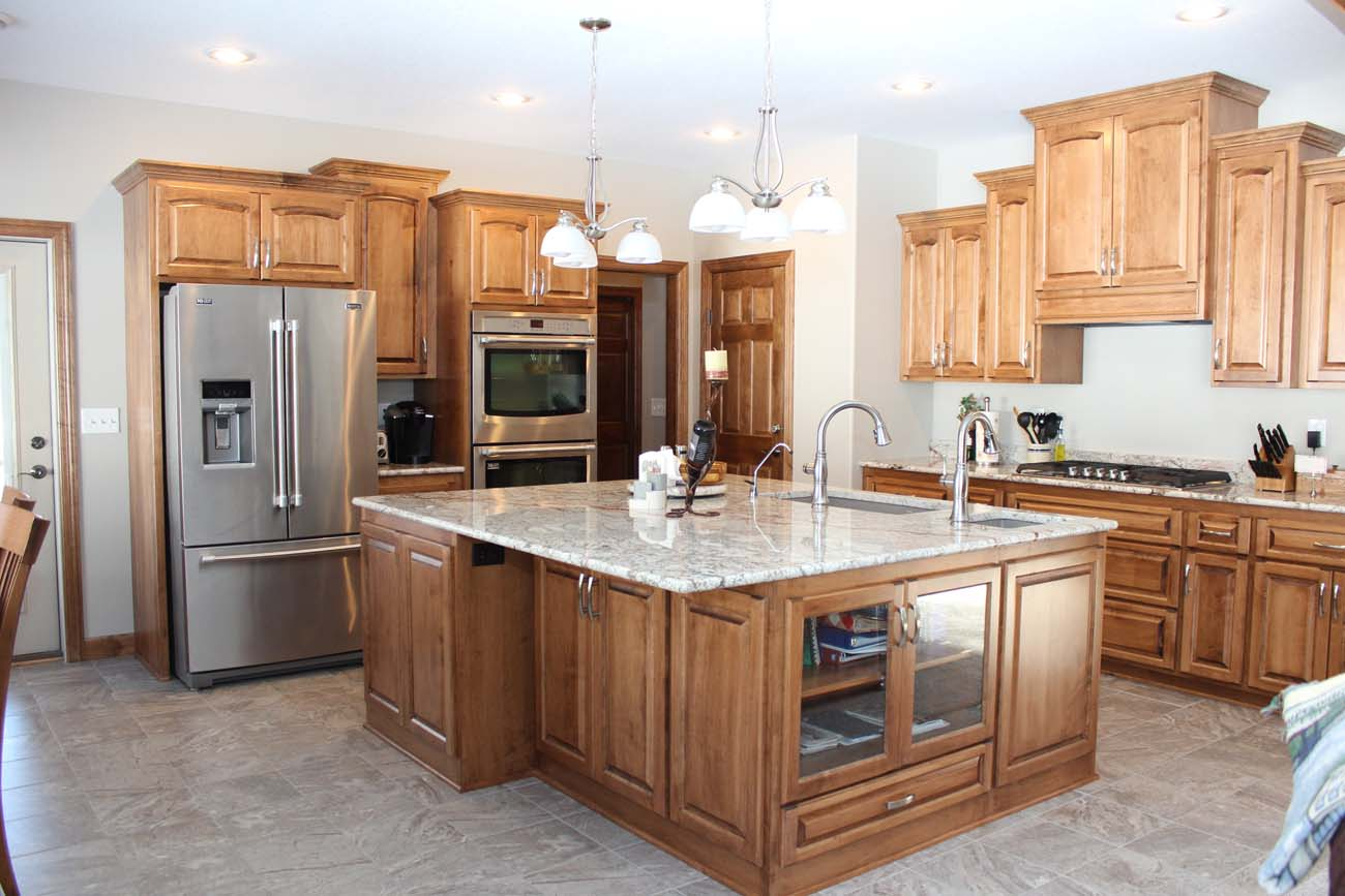 A kitchen with wooden cabinets , granite counter tops , stainless steel appliances and a large island.