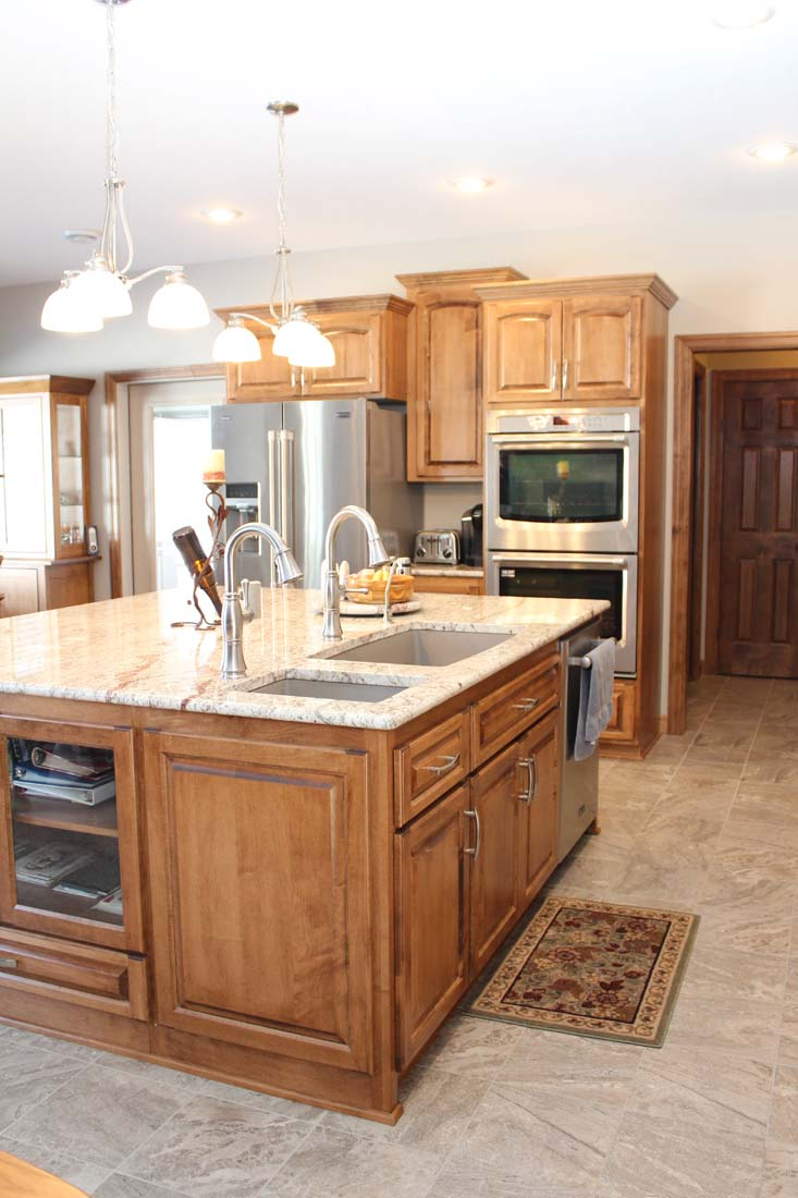 A kitchen with wooden cabinets , granite counter tops , and stainless steel appliances.