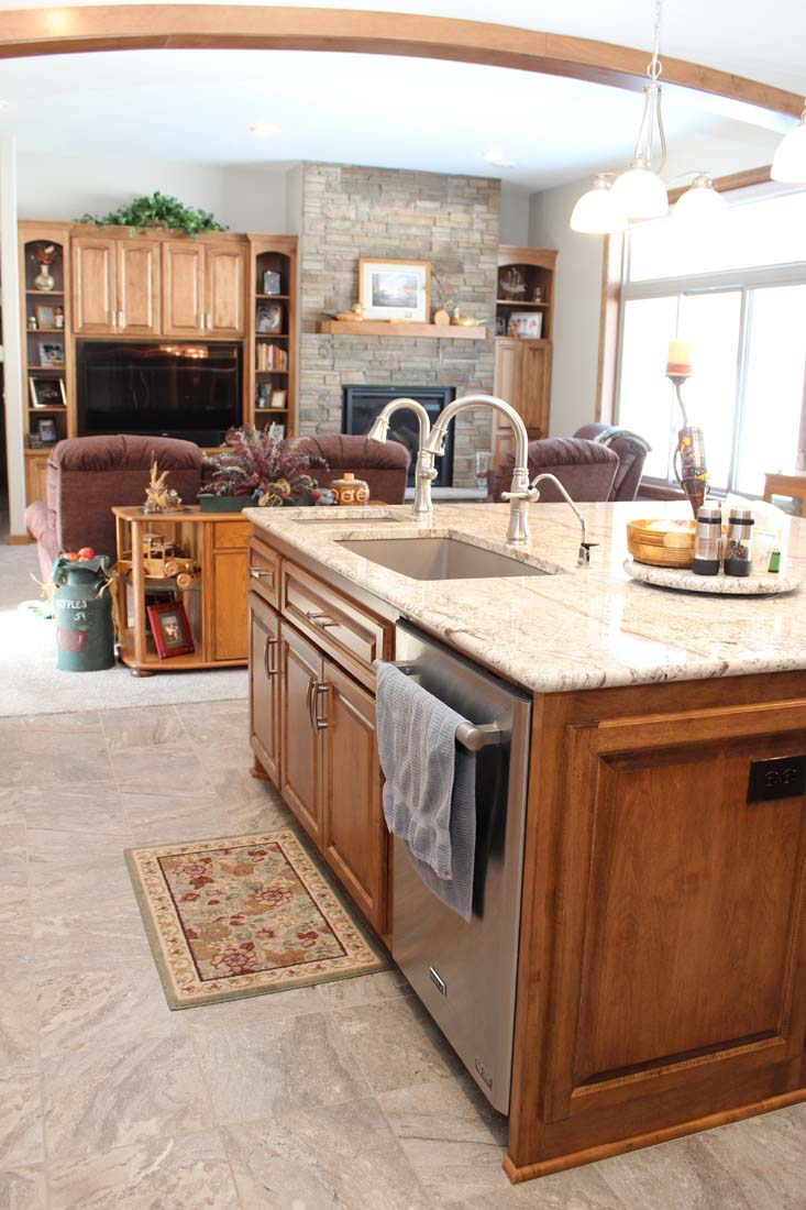 A kitchen with a large island and a sink in a living room.