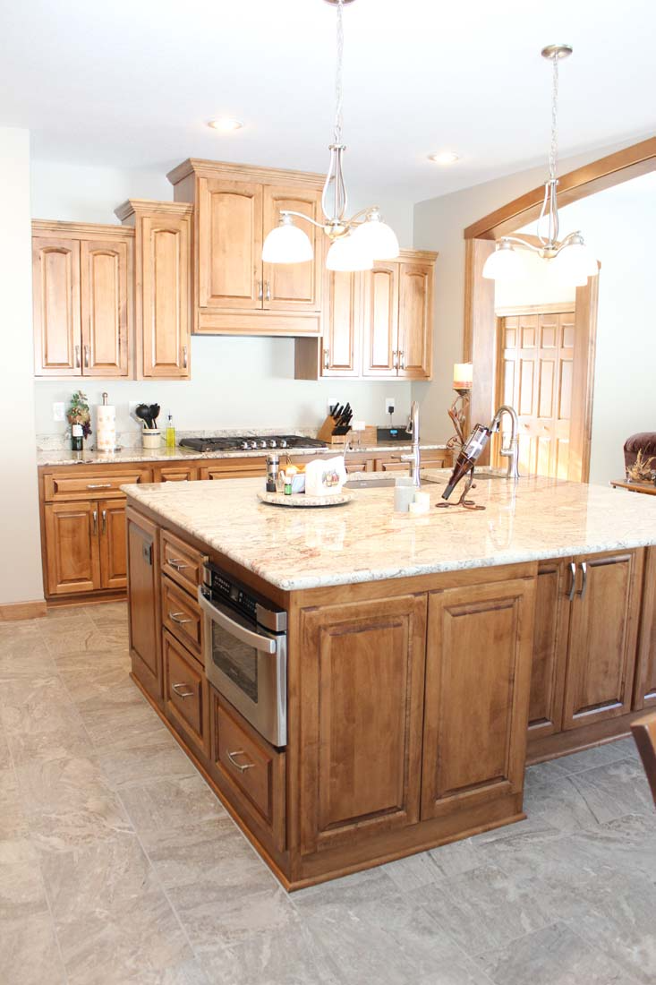 A kitchen with wooden cabinets and a large island in the middle.