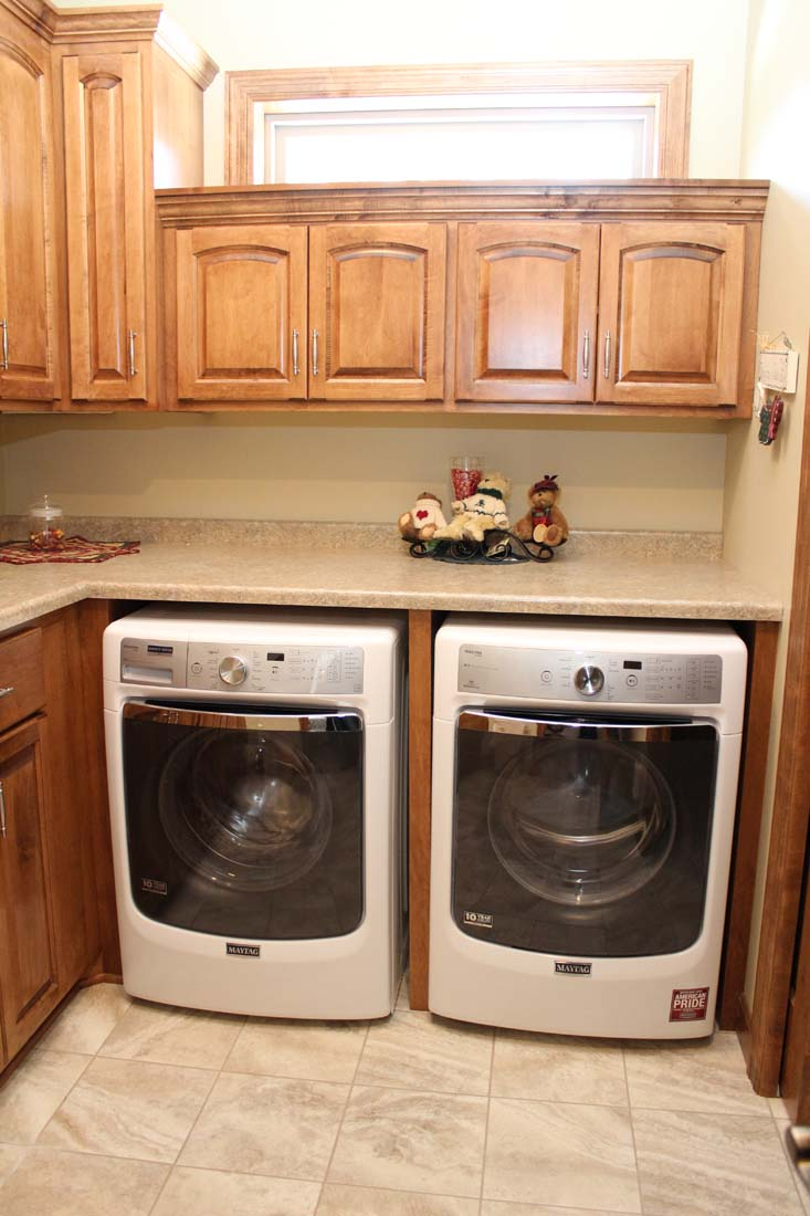 A laundry room with two washers and dryers under a window.