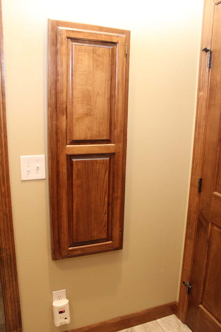 A wooden cabinet is hanging on a wall next to a door.