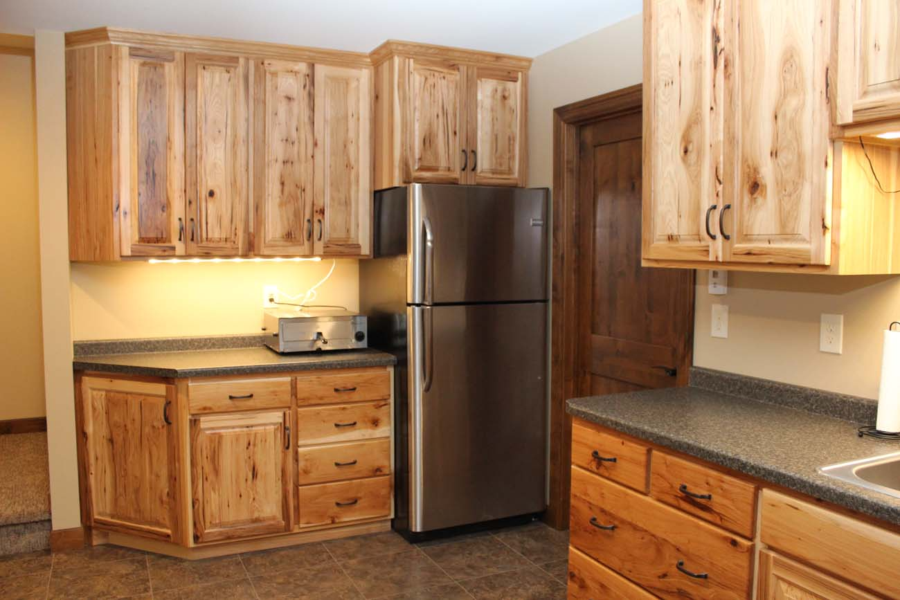 A kitchen with wooden cabinets and a stainless steel refrigerator.