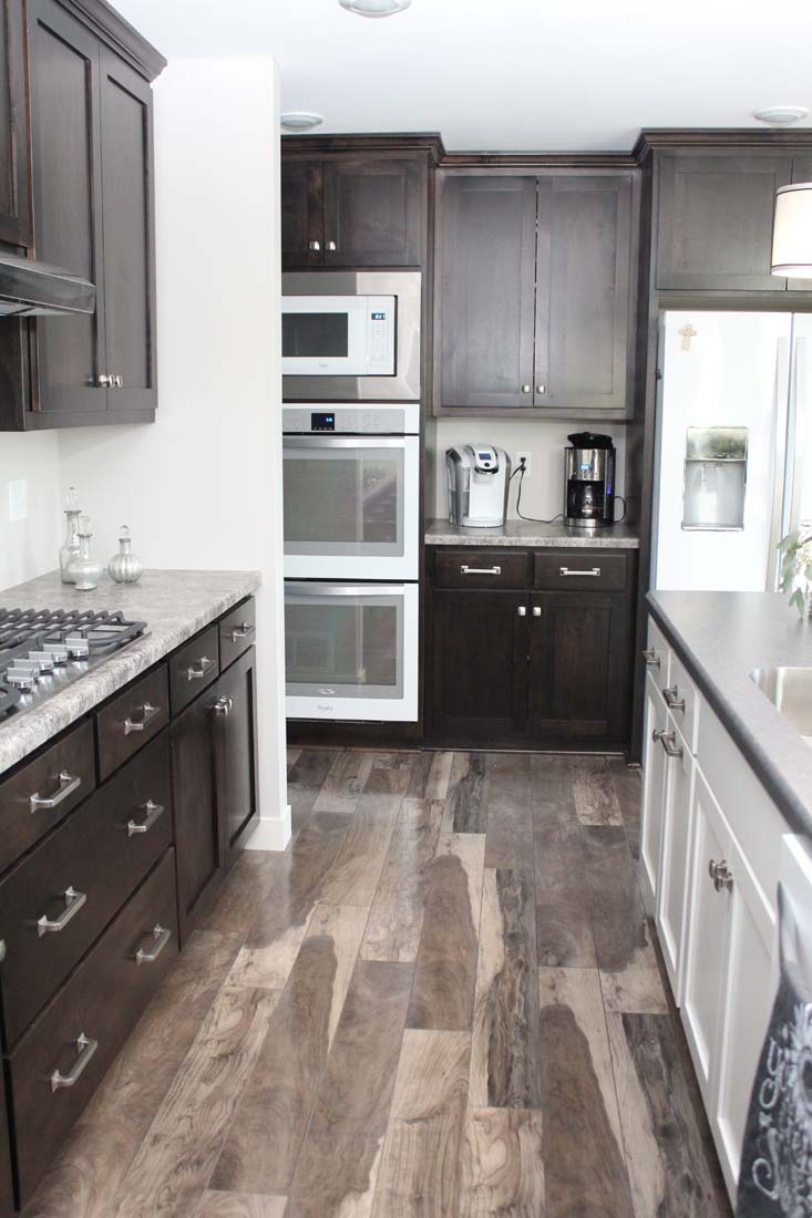 A kitchen with wooden cabinets , a stove top oven , a microwave , and a sink.