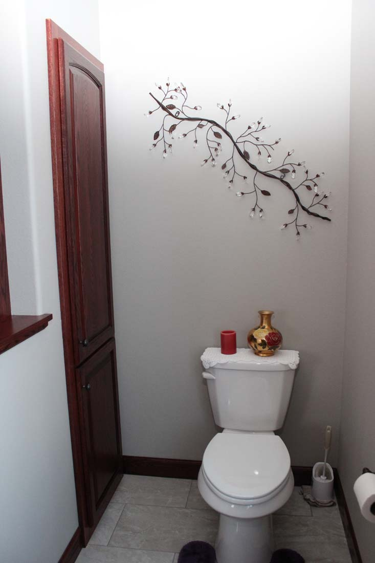 A bathroom with a toilet and a vase on the wall