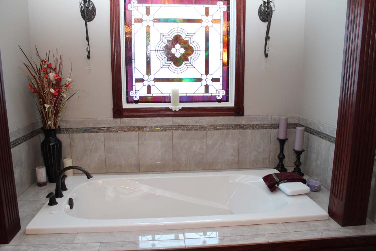 A bathtub in a bathroom with a stained glass window above it