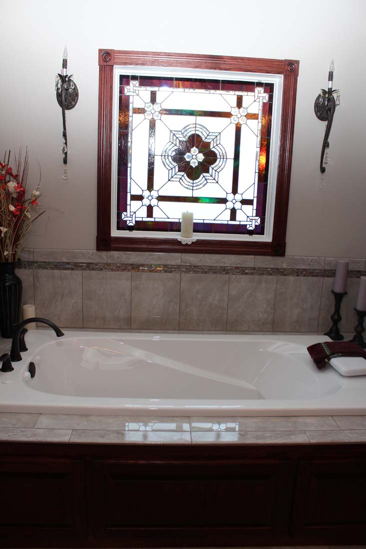 A bathtub with a stained glass window above it