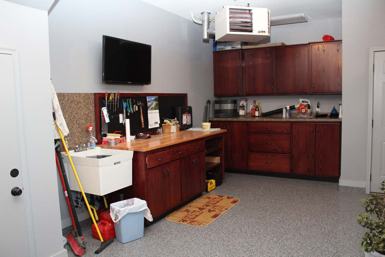 A kitchen with a sink and a television on the wall