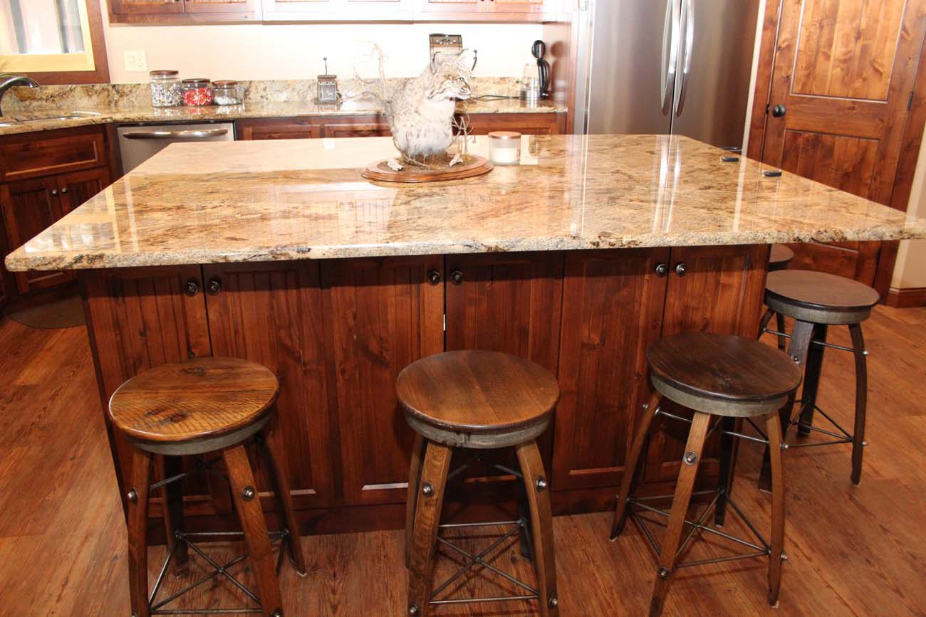 A kitchen with a large island and three stools.