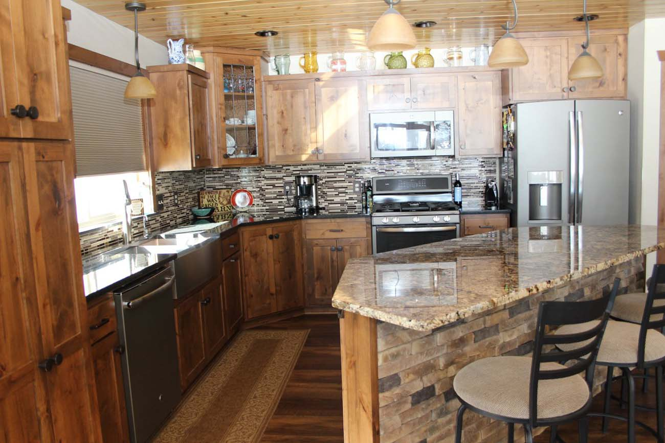 A kitchen with wooden cabinets , granite counter tops , stainless steel appliances and a large island.