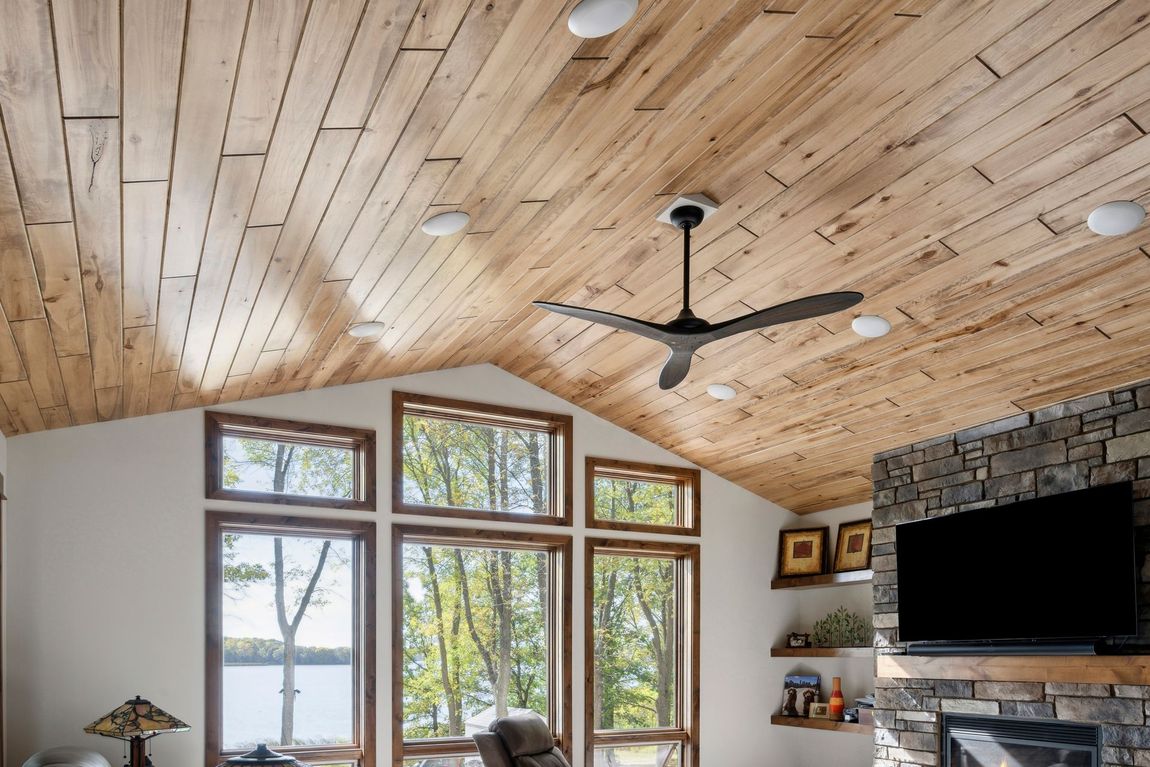 A living room with a wooden ceiling and a ceiling fan.