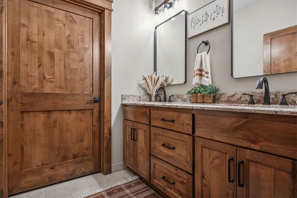 A bathroom with two sinks , two mirrors , and wooden cabinets.