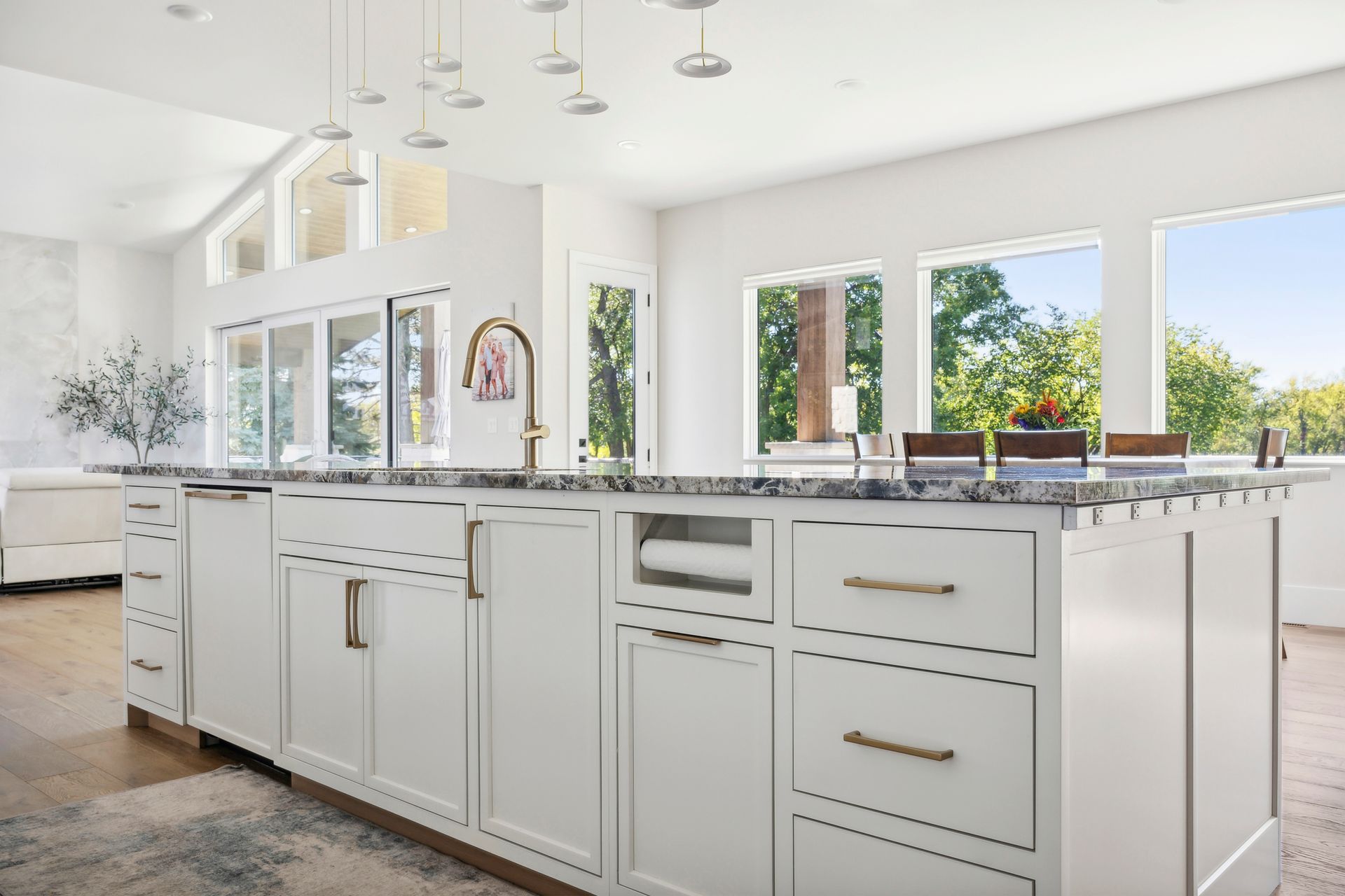 A kitchen with white cabinets , granite counter tops , and a large island.