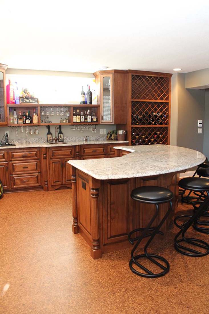 A kitchen with a large island and stools and a wine rack.
