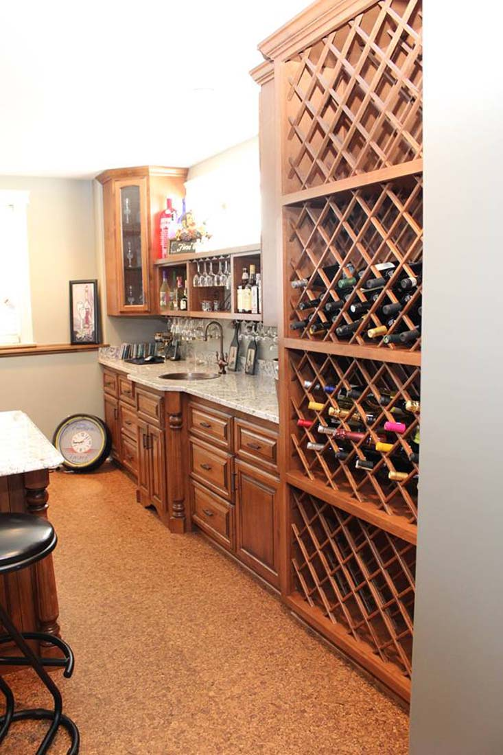 A kitchen with a lot of wine bottles on the shelves.