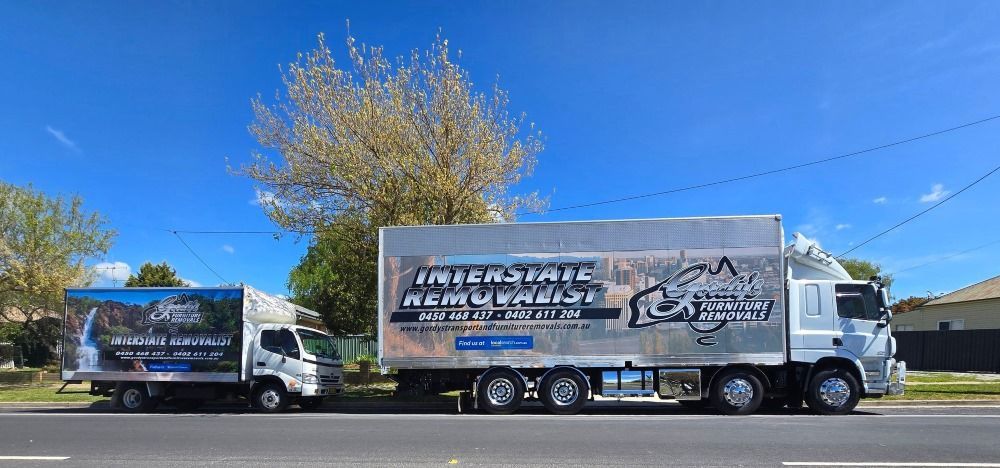 Two Moving Trucks Are Parked on the Side of the Road — Gordy's Furniture Removals in Bathurst, NSW