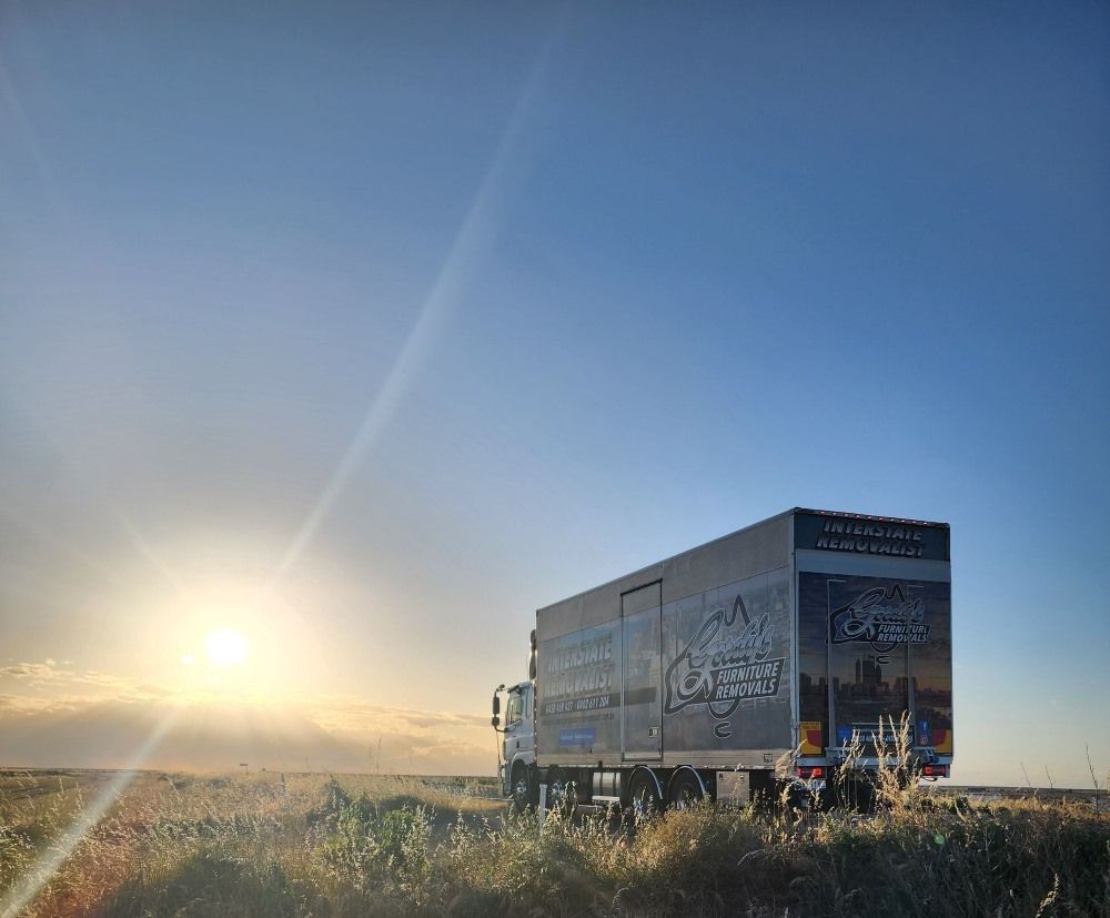 A Semi Truck is Parked in a Field at Sunset — Gordy's Furniture Removals in Goulburn, NSW