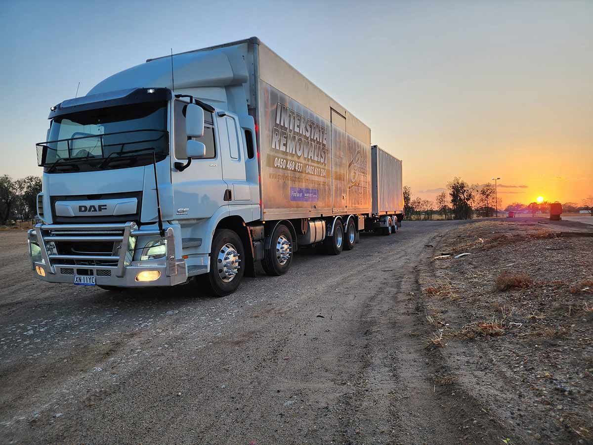 A large truck is driving down a dirt road at sunset — Gordy's Furniture Removals in Southern Highlands, NSW