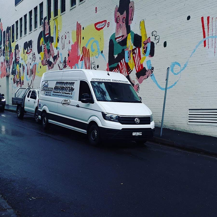 A White Van Is Parked In Front Of A Wall With Graffiti On It — Gordy's Furniture Removals in Bathurst, NSW