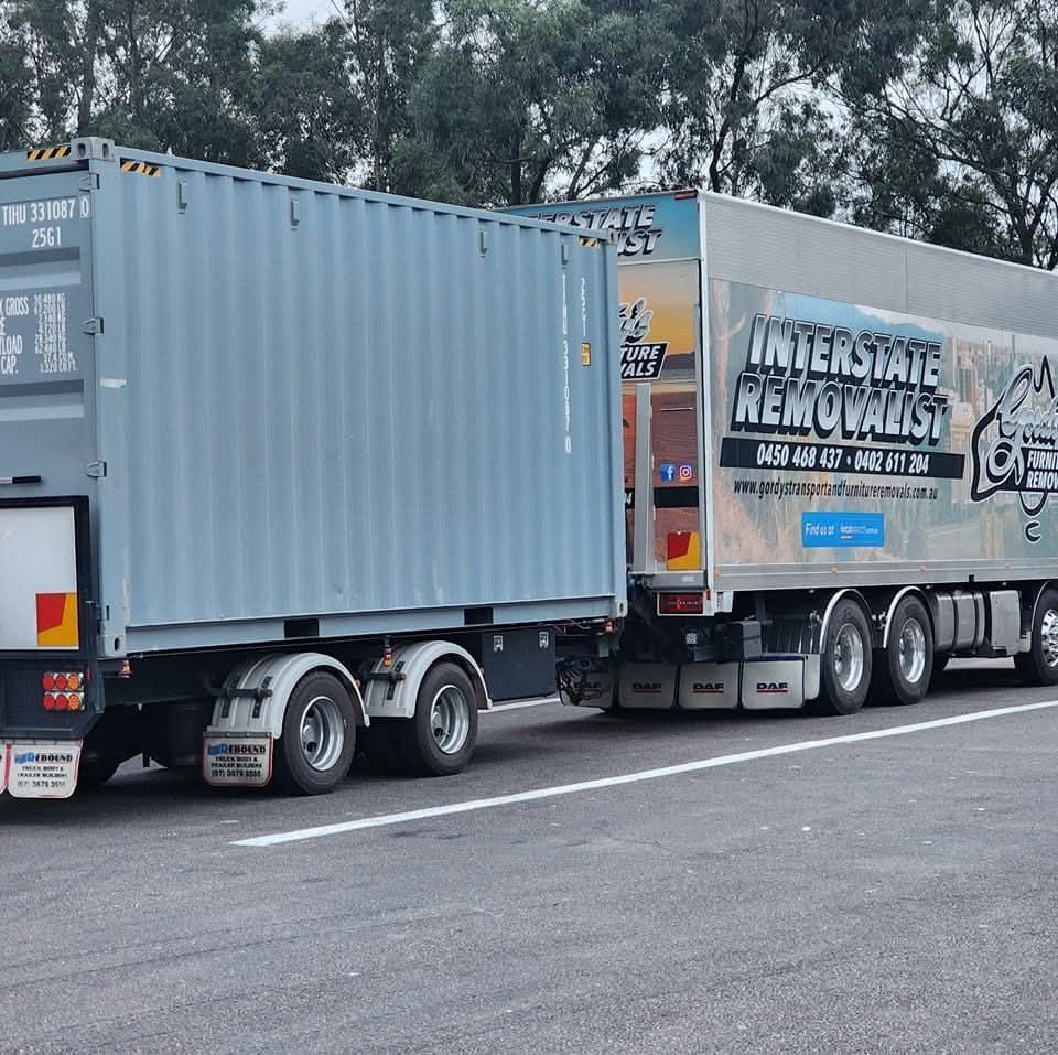 An Interstate Removalist Truck is Parked Next to a Shipping Container — Gordy's Furniture Removals in Bathurst, NSW