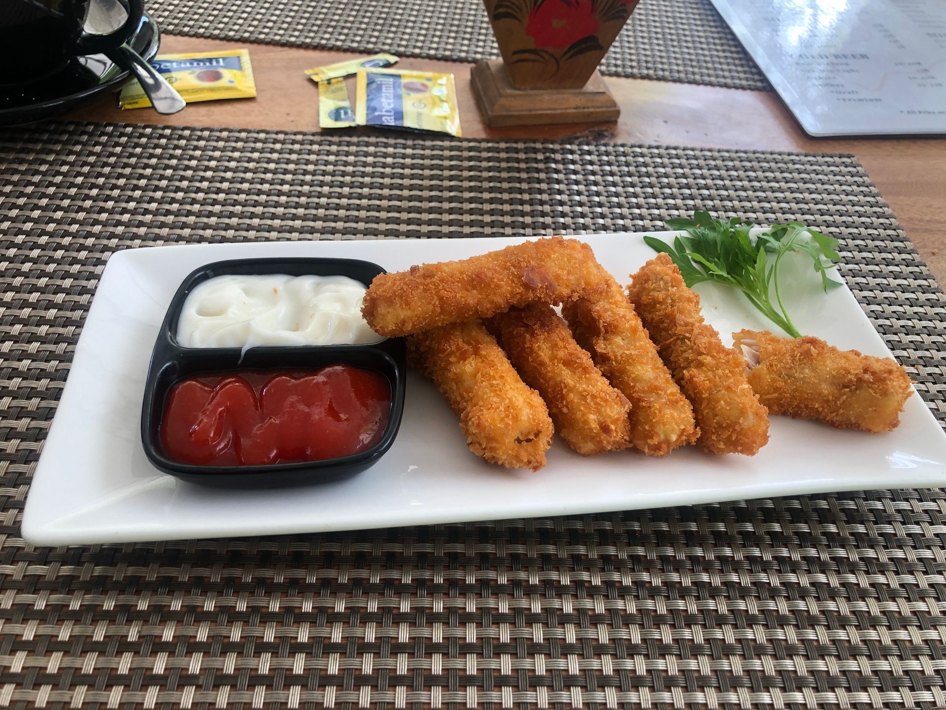 A white plate topped with fried mozzarella sticks and ketchup