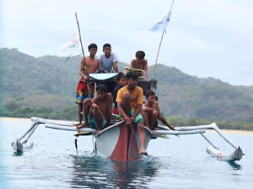 A group of young men are sitting on a boat in the water