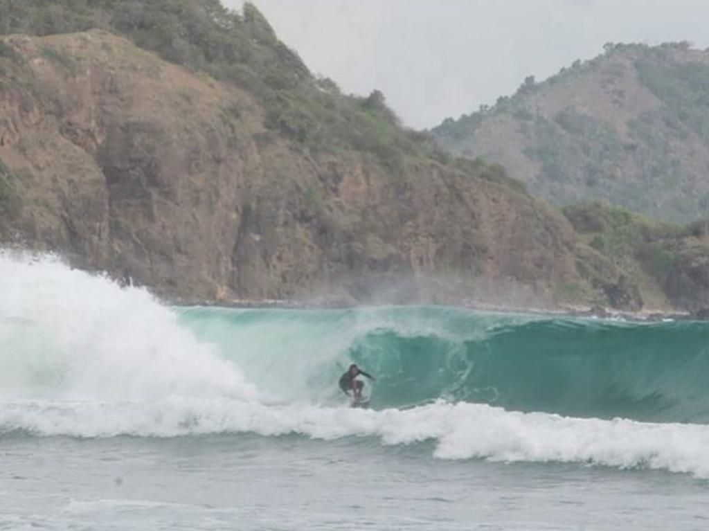 A man is riding a wave on a surfboard in the ocean.