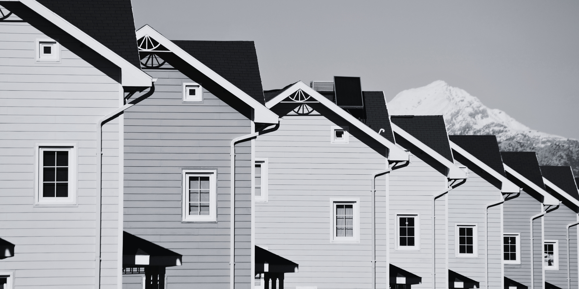 Row of houses with a snowy mountain in the background. Black and white photo.