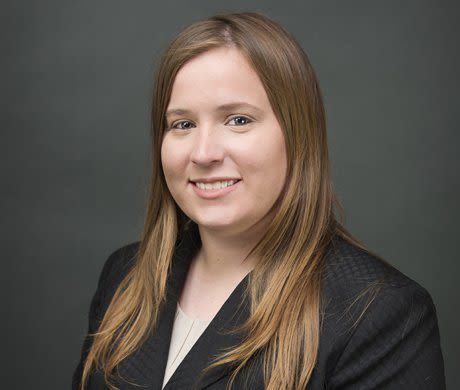 A woman in a black jacket and white shirt is smiling for the camera.