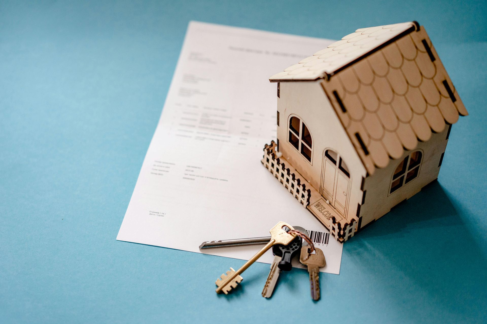 A small wooden house with keys on top of a piece of paper.