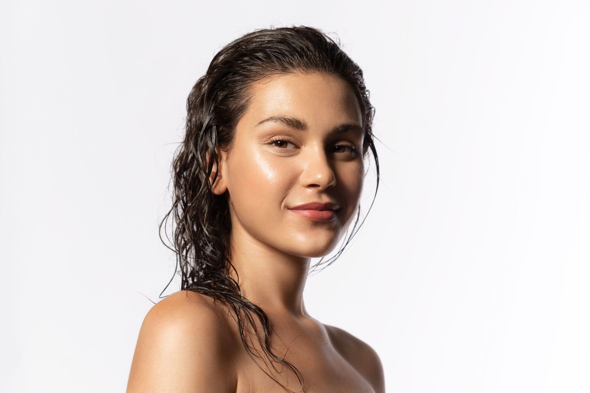 a close up of a woman 's face with wet hair on a white background .