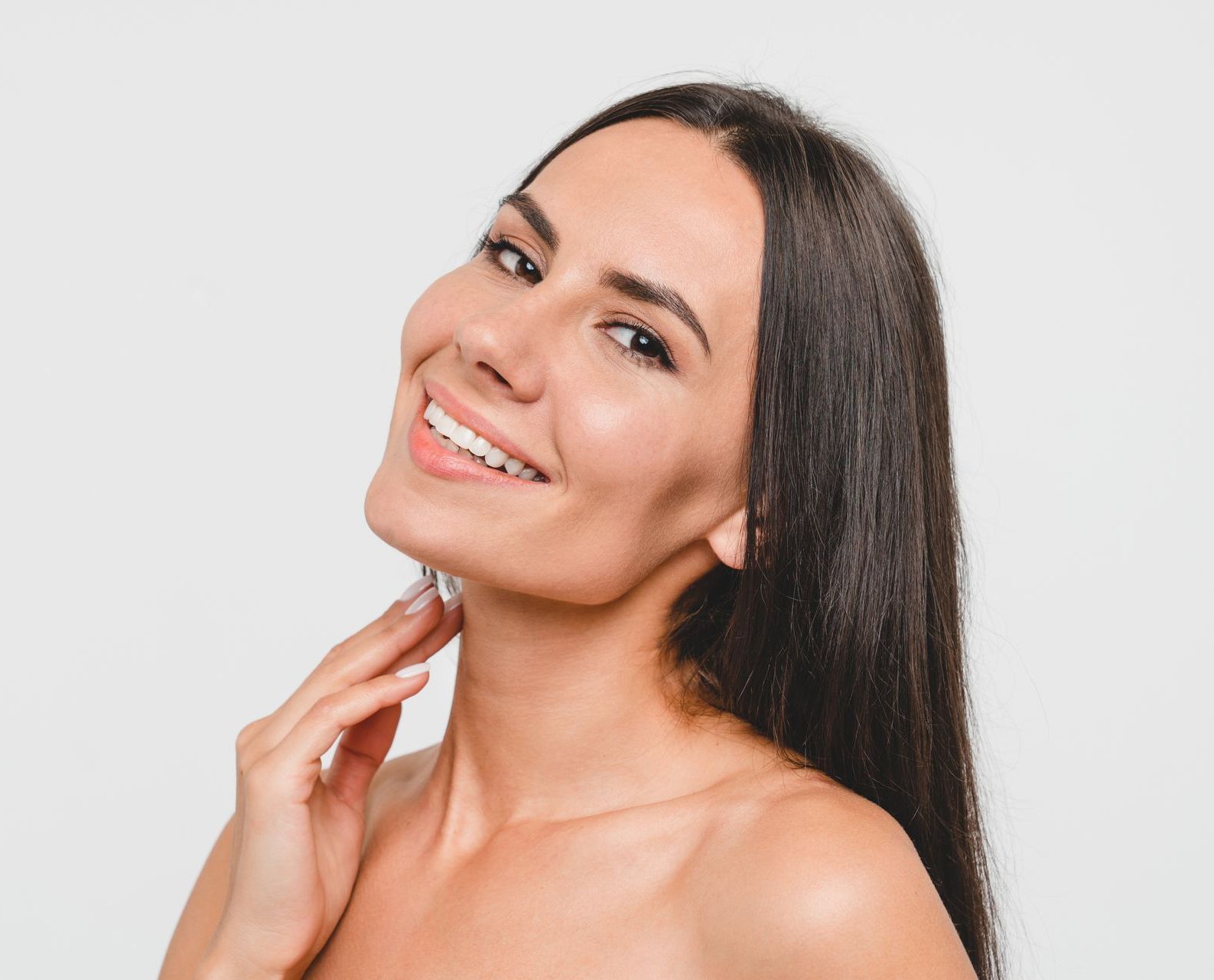 a woman with long hair is smiling and touching her neck 