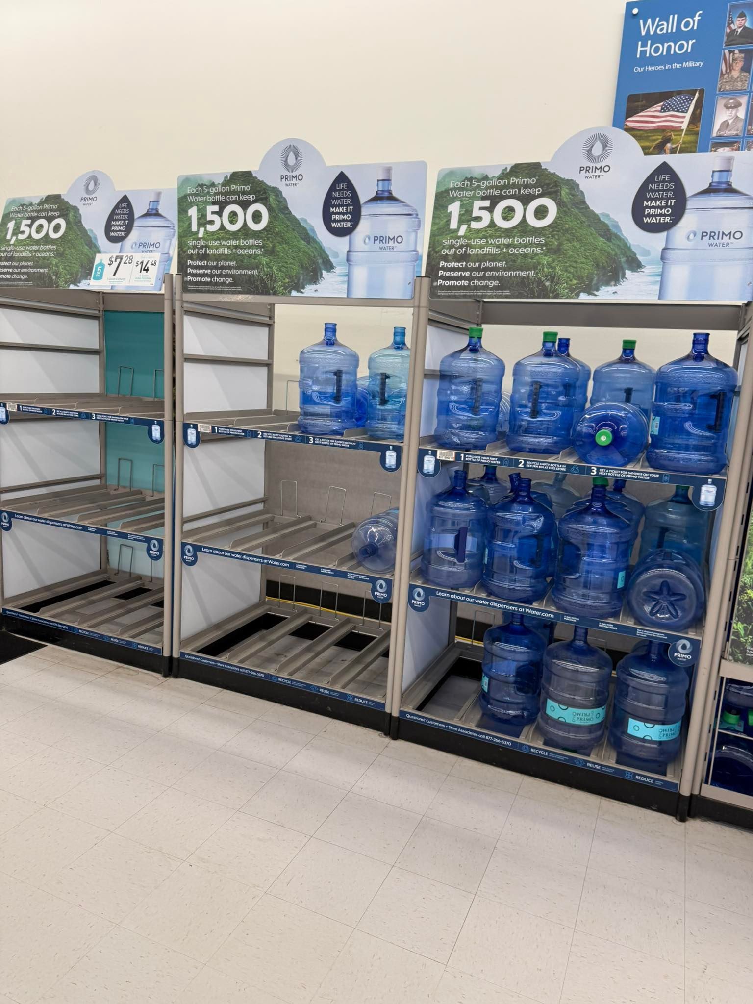 Shelves with large blue water jugs in a store. Some shelves are empty, others are full or partially filled.