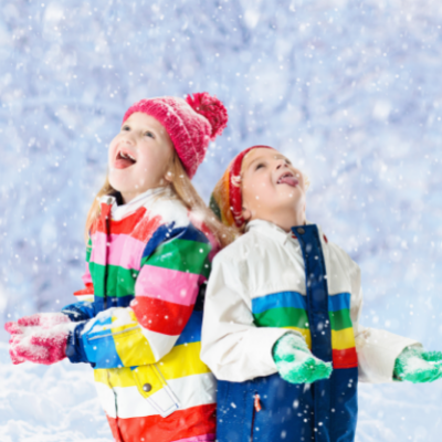Two children in colorful jackets looking up at the snowy sky with their mouths open.