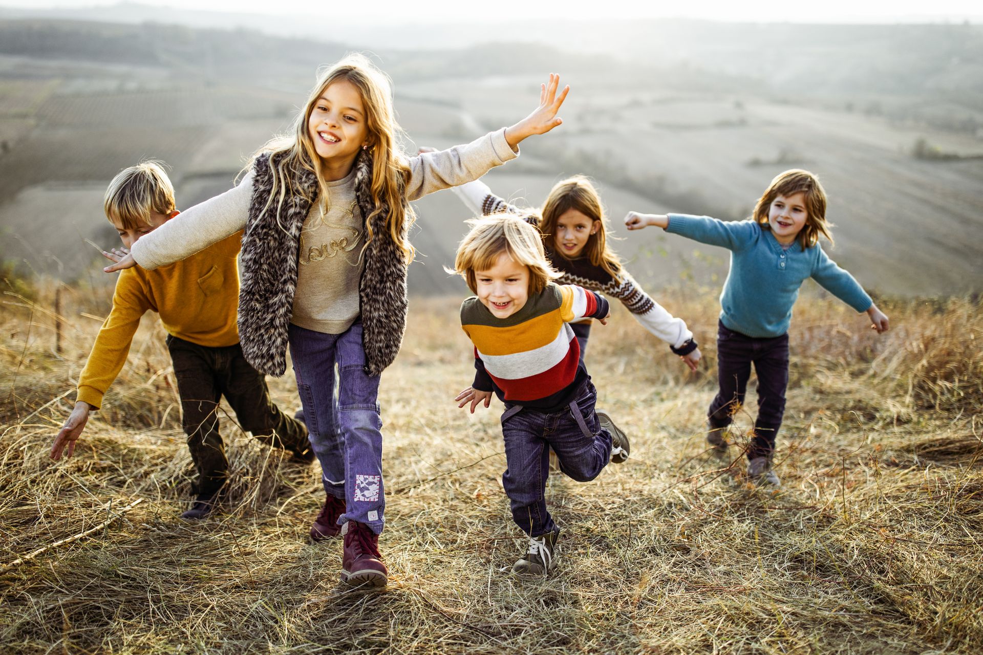 Five young children climbing up a hill.