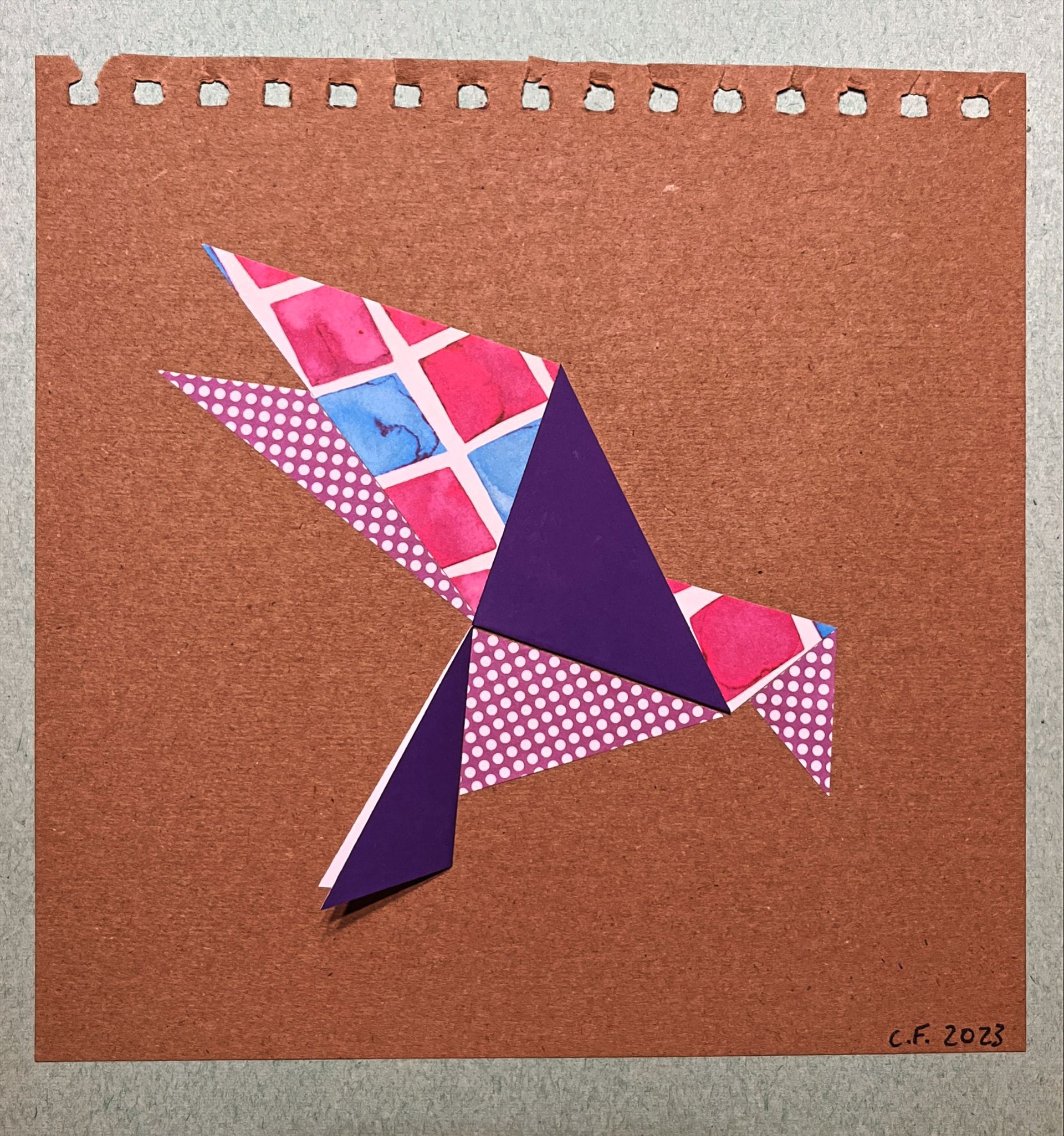 Origami bird made from patterned paper on a brown background.