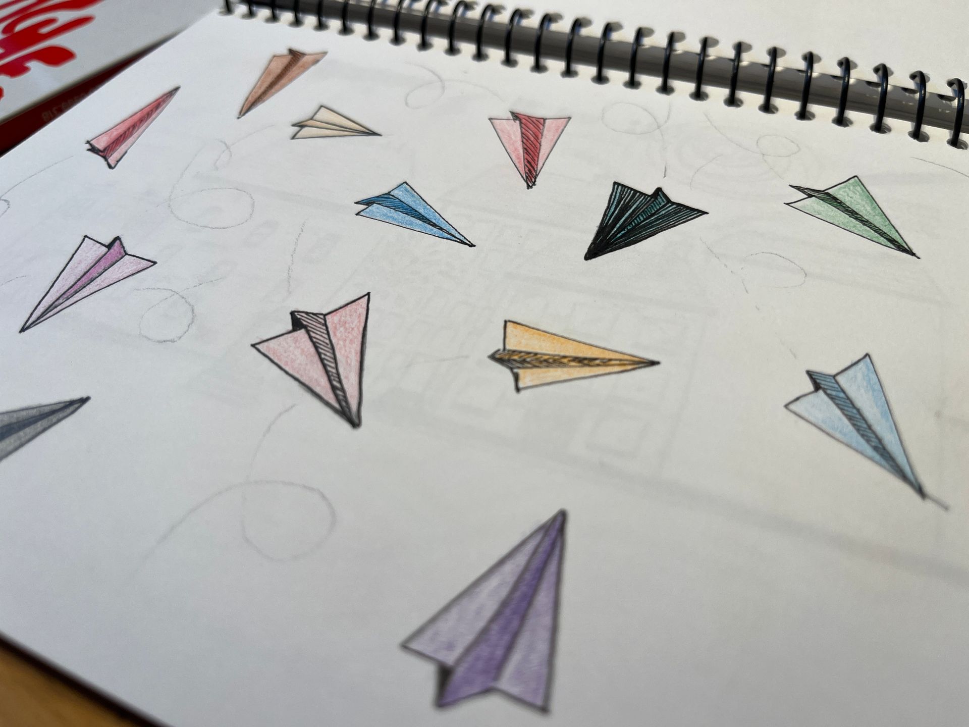 Colorful paper airplanes drawn on white notebook paper.