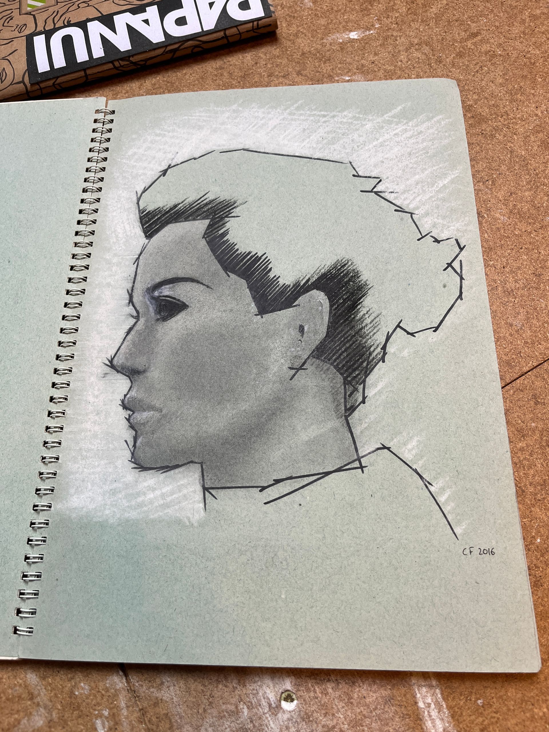 Sketch of a person's profile on a spiral-bound notebook.