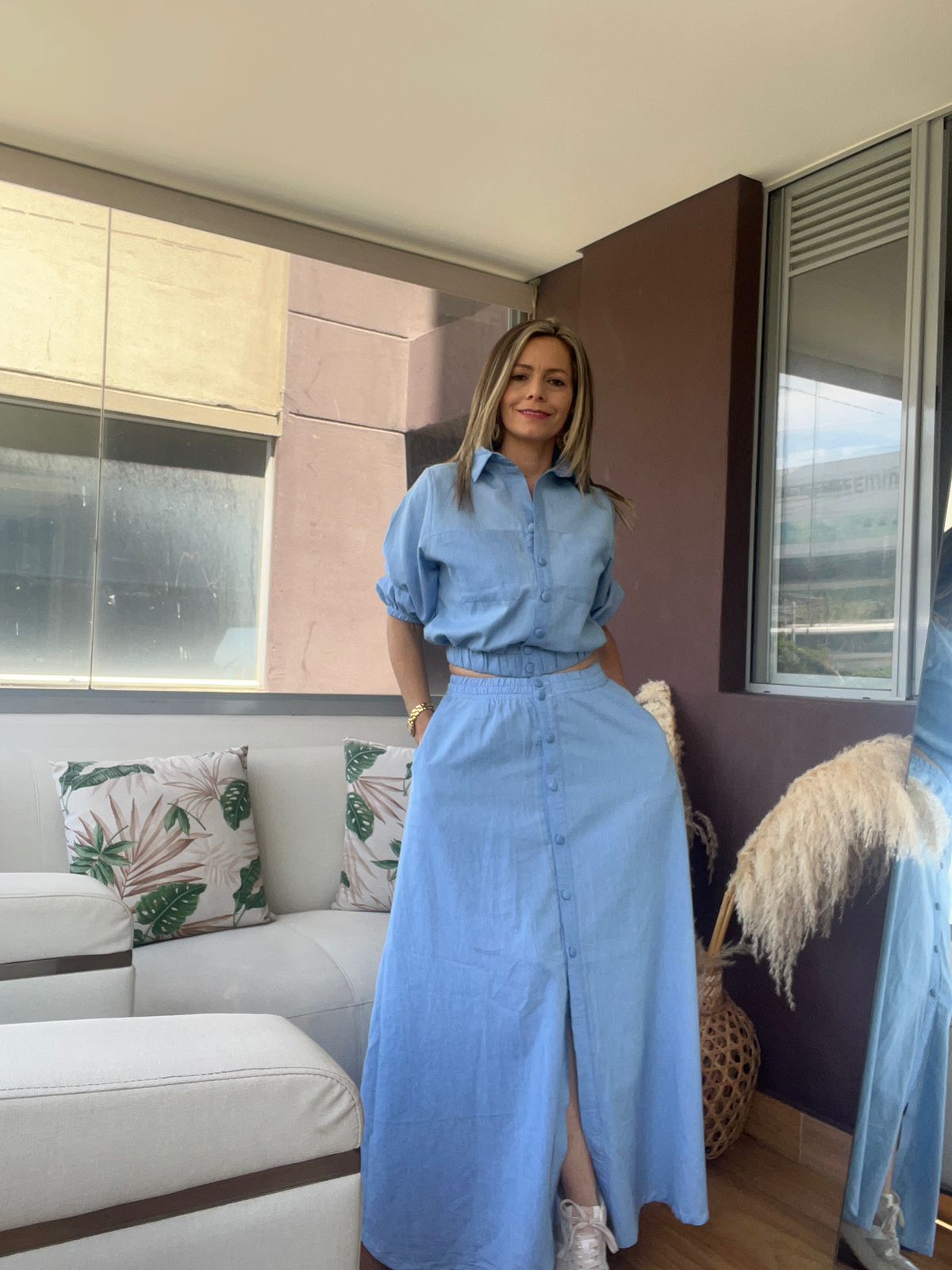 Mujer con una camisa abotonada azul claro y un conjunto de falda larga
