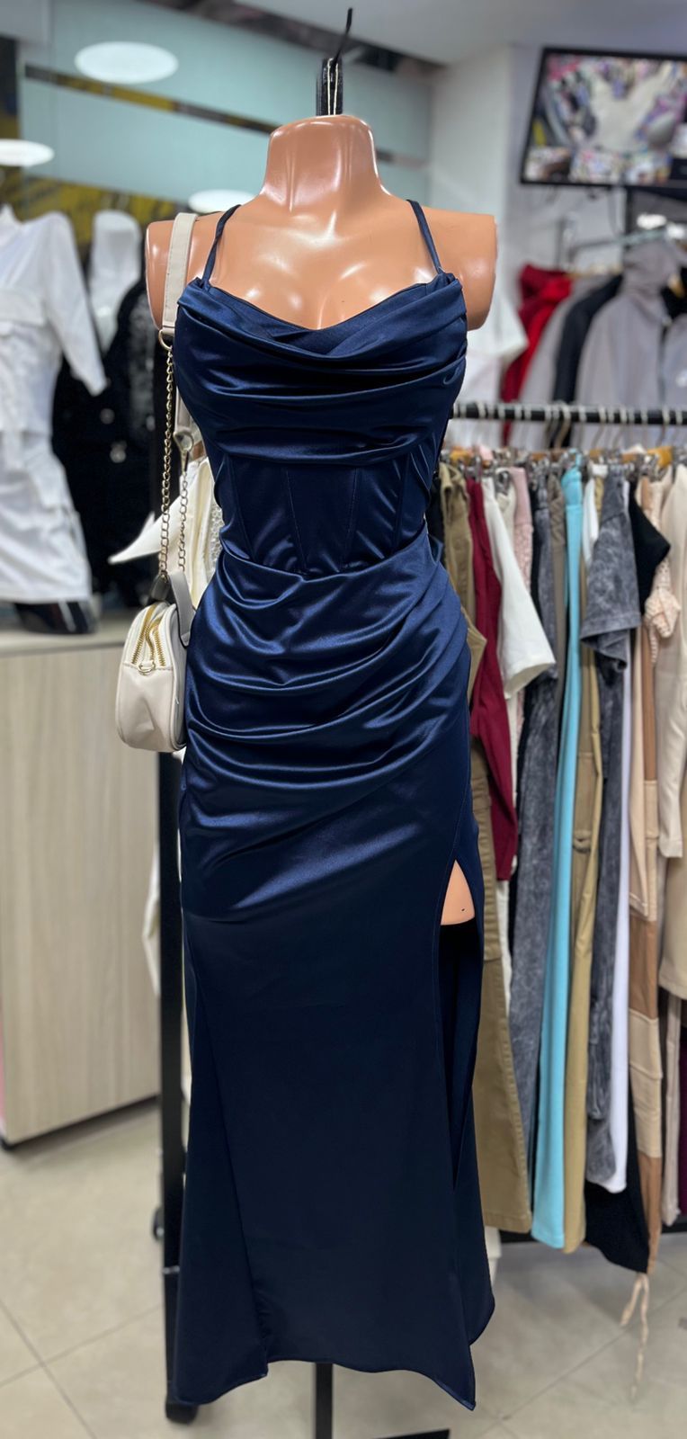Un vestido de satén azul marino sobre un maniquí con tirantes finos y una abertura en el muslo.