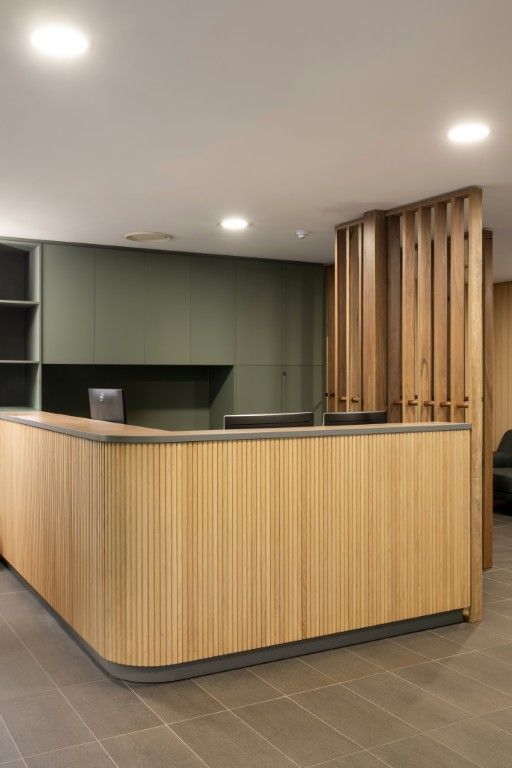 Modern reception desk with vertical wooden slats, gray cabinetry, and wooden partition screen in a minimalist office. — Foreshore Kitchens in Coolum Beach, QLD
