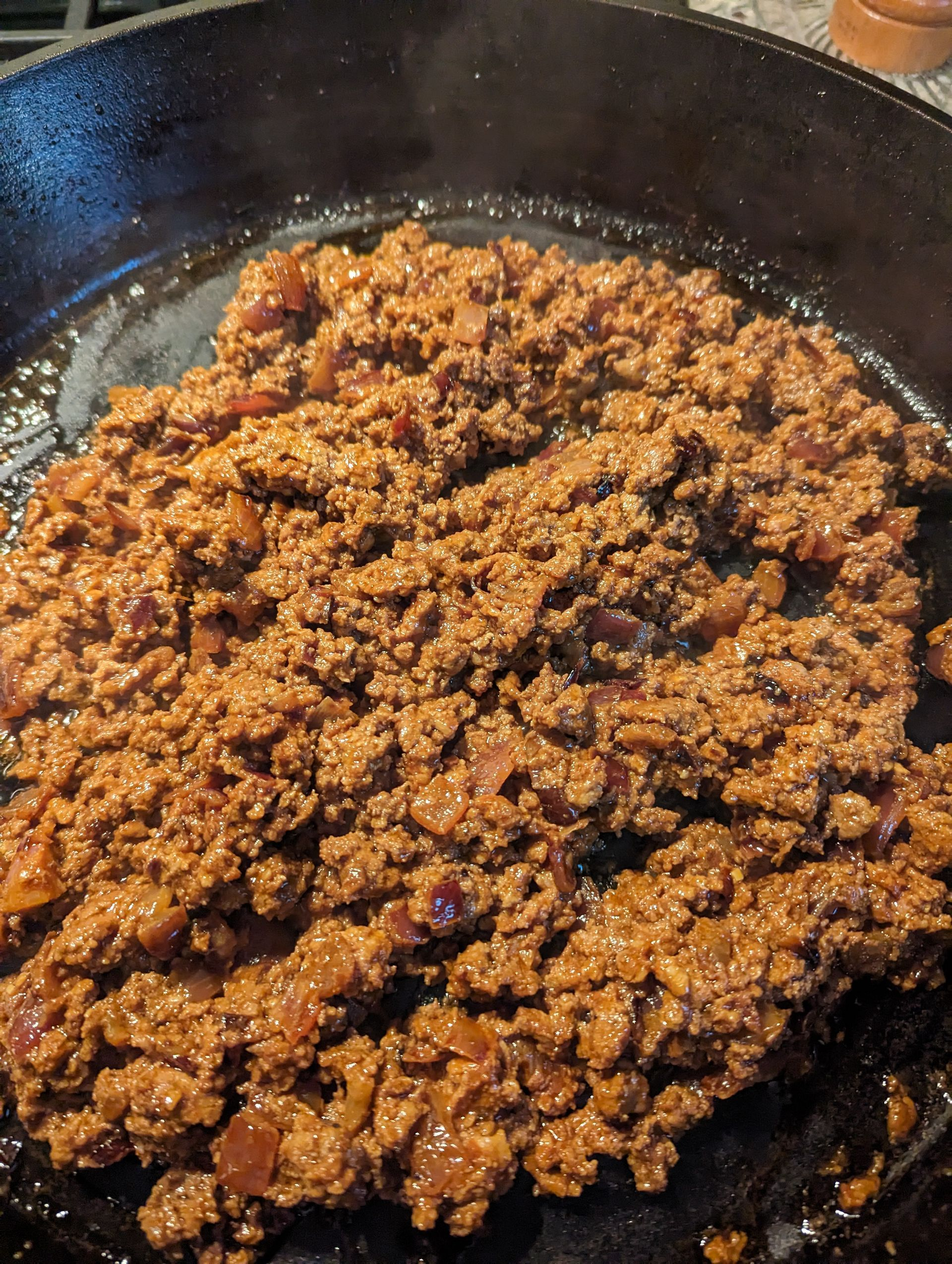 Ground beef is being cooked in a skillet on a stove.