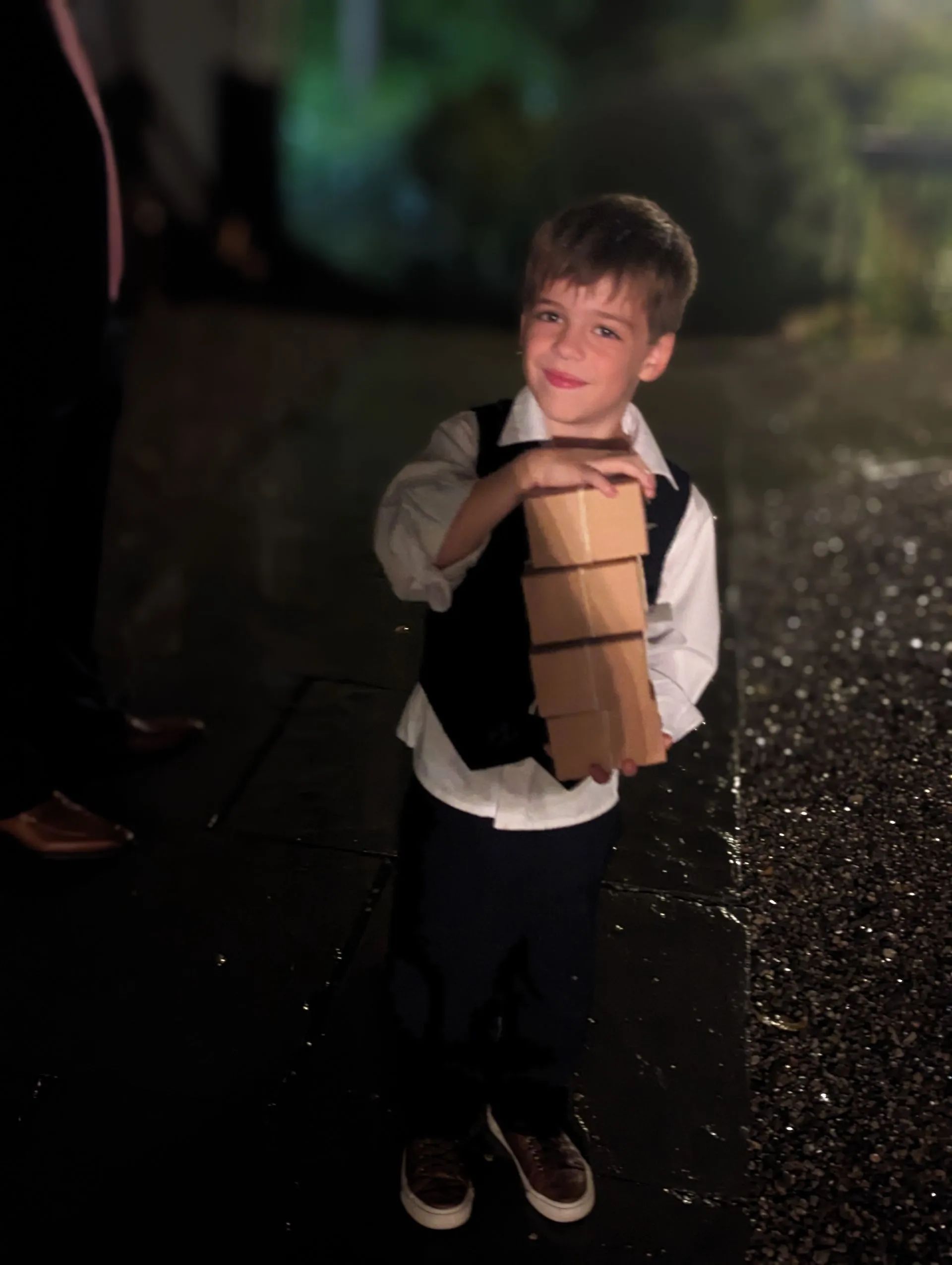A young boy is holding a stack of books in his hands