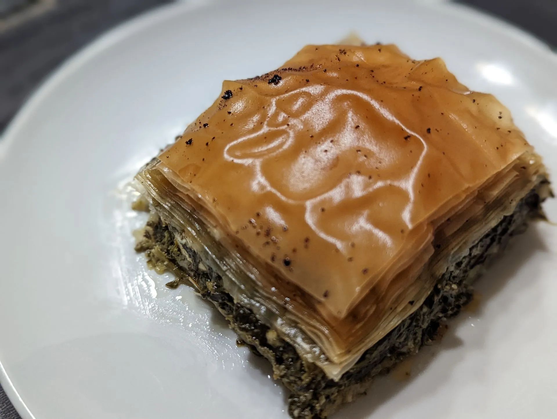 A piece of baklava is on a white plate.