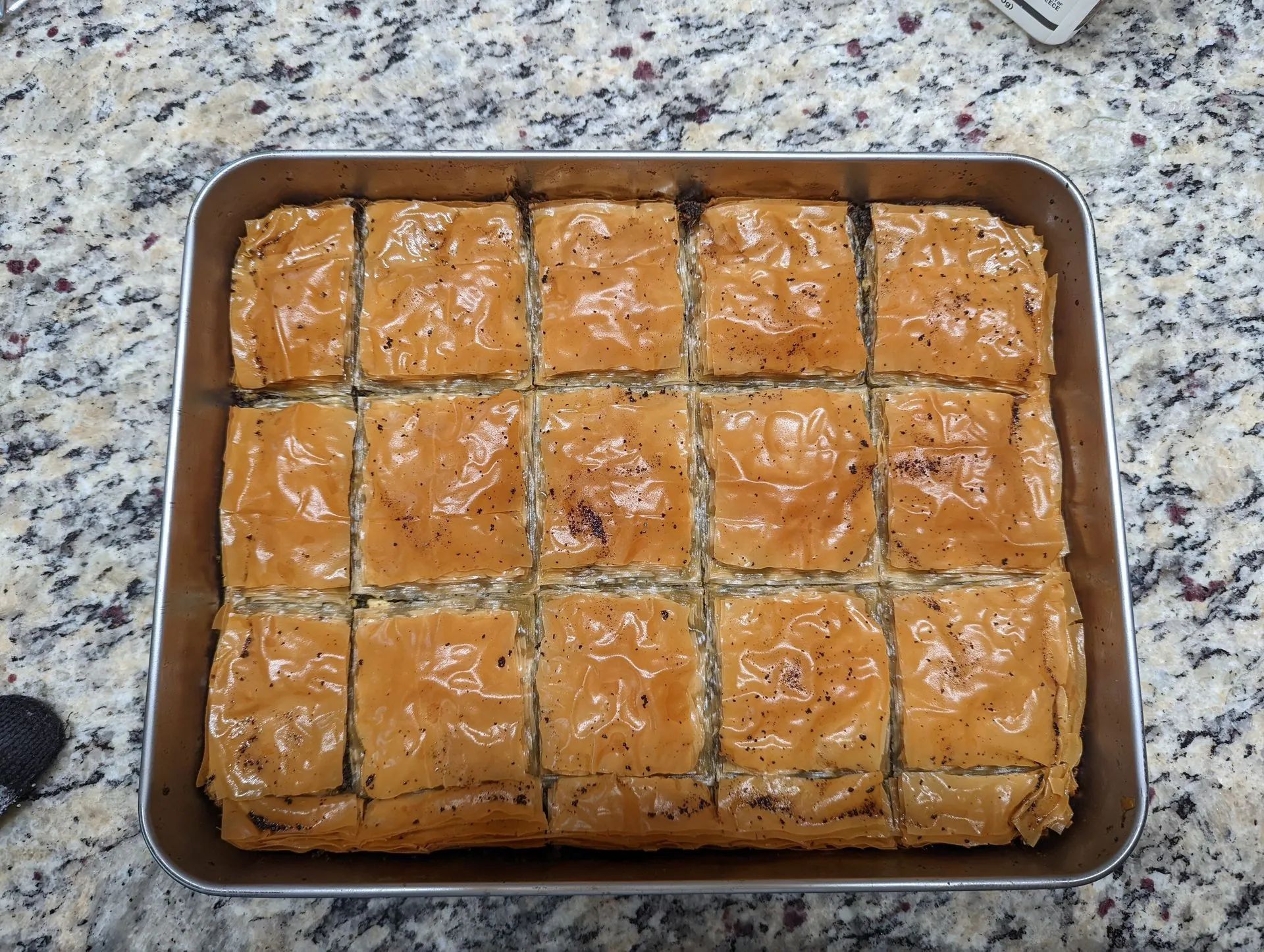A pan of baklava is sitting on a granite counter top.