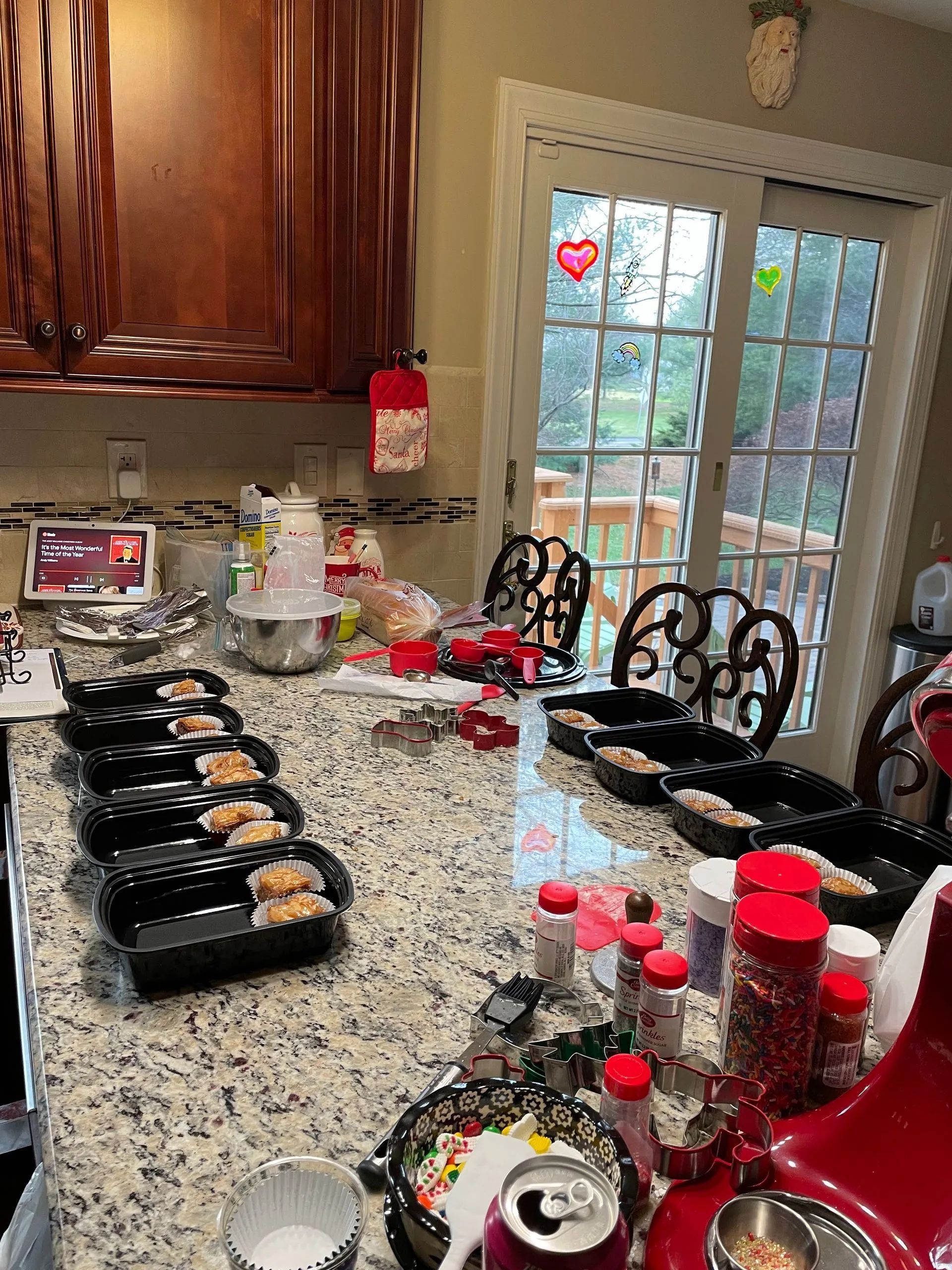 A kitchen with a lot of food on the counter and a sliding glass door.